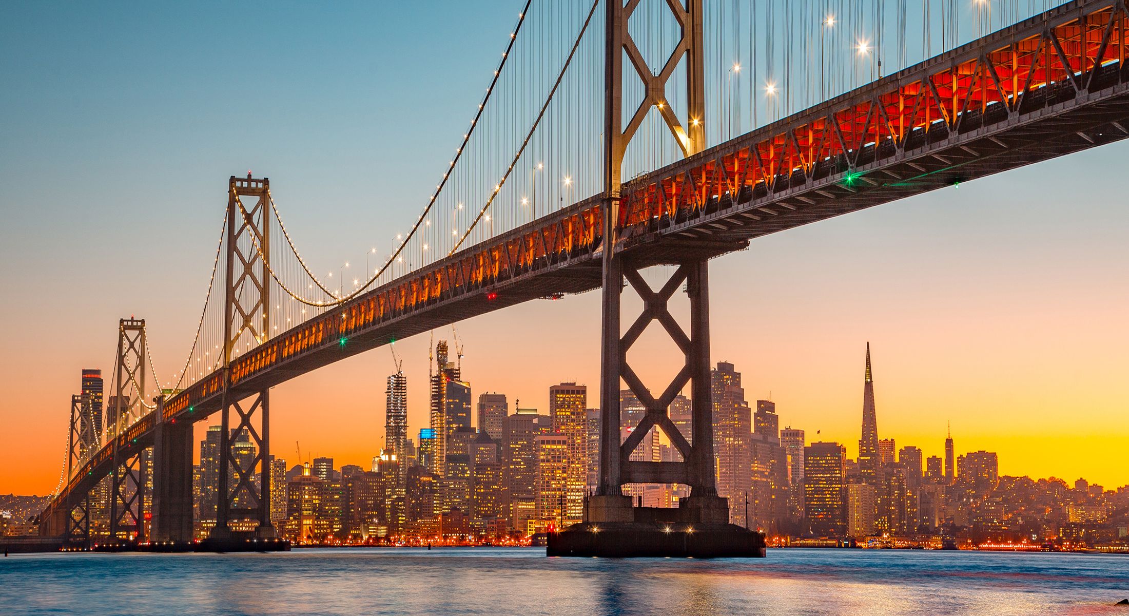 bridge with city behind it at dusk